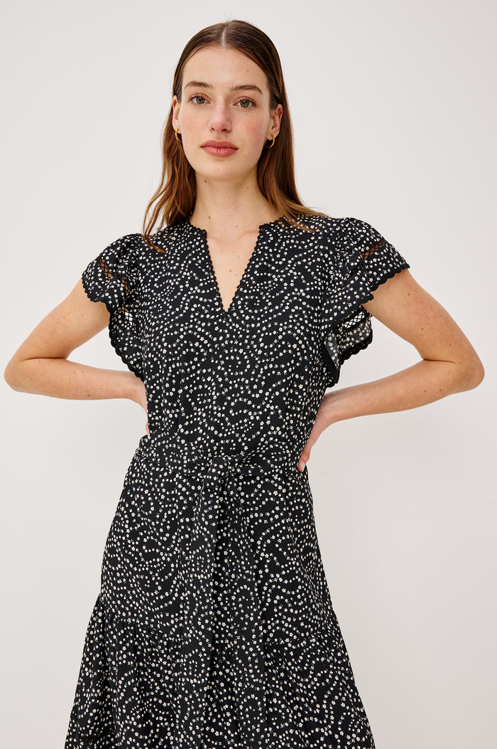 Gia Mini Dress in Crinkle Poplin With Adjustable Waist Ties Split V-Neck Collar Wide Short Sleeves Ladder and Crochet Trim Detailing and Relaxed FIt in Mini Chain Daisies Colorway - Upper Body Front View Featured on Model