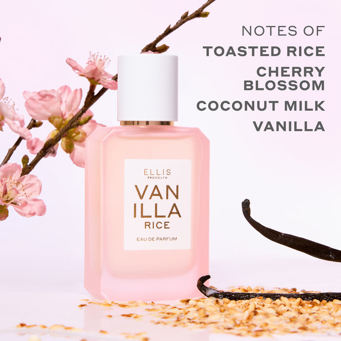 VANILLA RICE Eau de Parfum 50ml next to toasted rice, vanilla beans, and pink sakura blossoms on a pink background with gray text that reads "Notes of toasted rice, cherry blossom, coconut milk, vanilla"