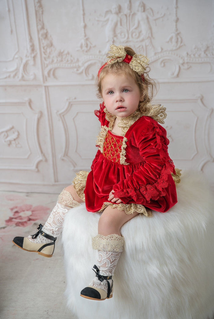 Baby wearing the Victoria red velvet hair sash with ivory lace bow and decorative jewel accents in a studio setting
