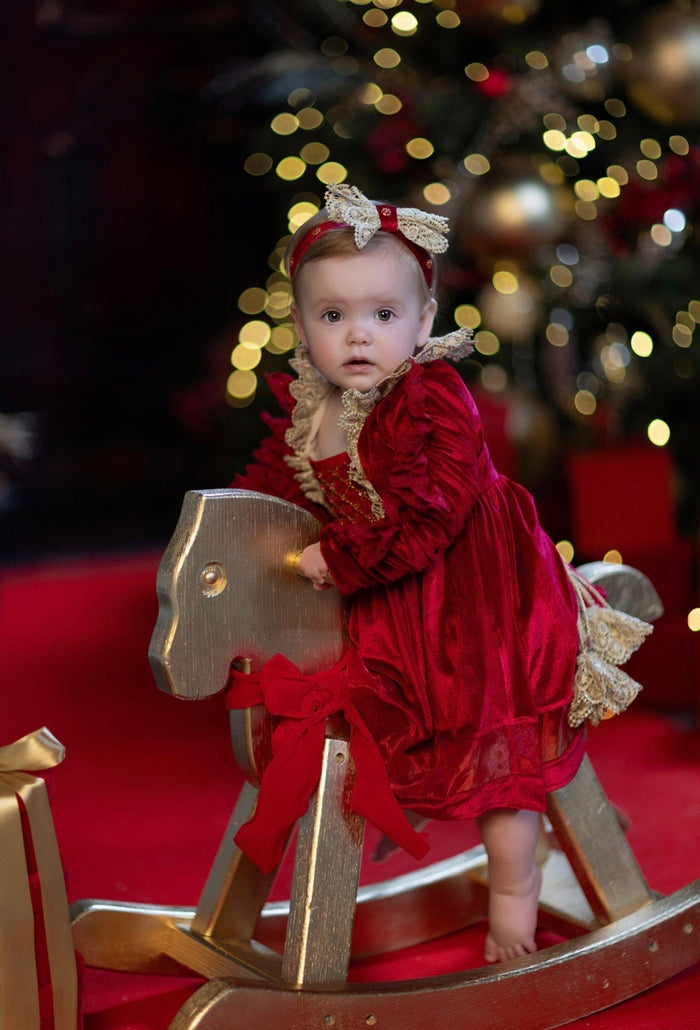 Victoria red velvet hair sash worn by a baby, highlighting the lace bow and rich velvet fabric